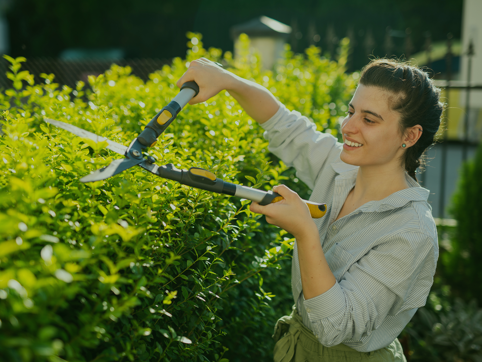 Smiling woman gardening in backyard