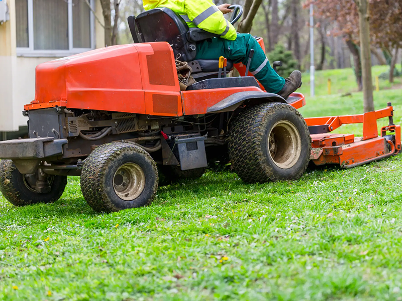 Riding lawn mower cutting green grass.